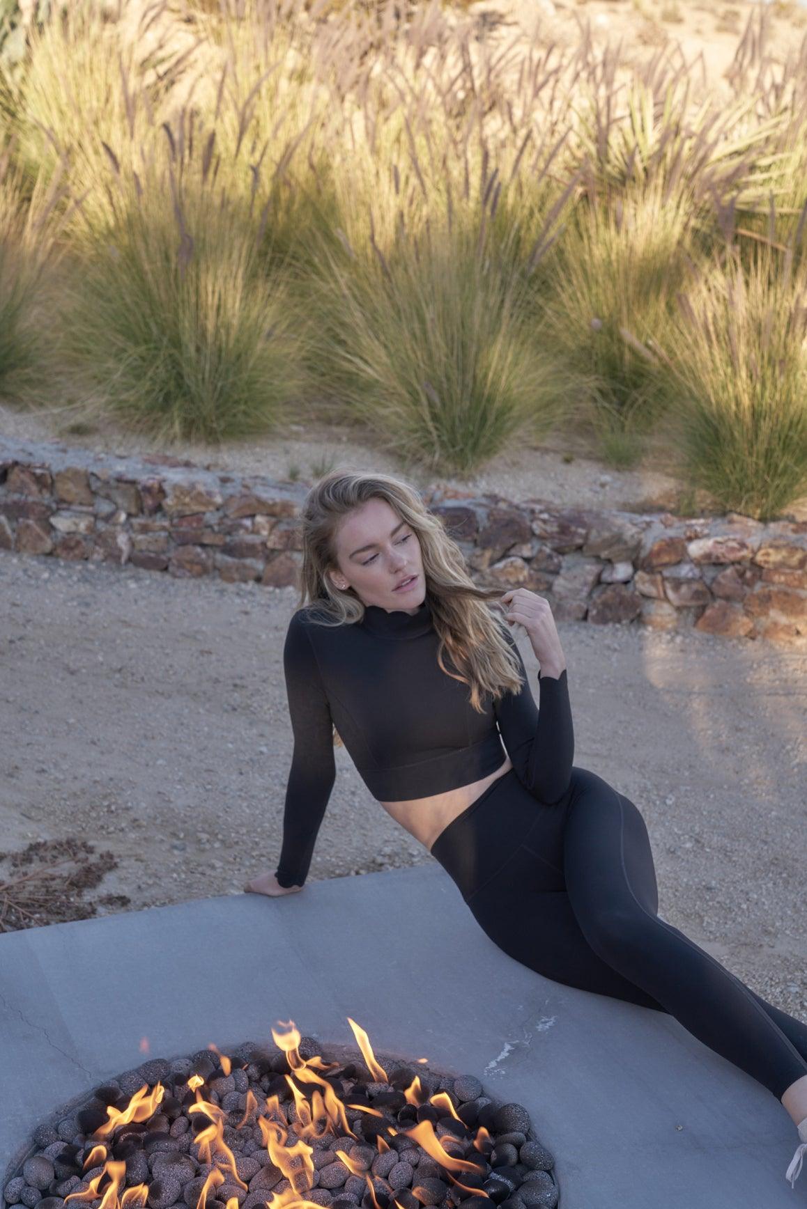 Black open-back long sleeve crop top by WISKII, featuring a stylish crop top design with a fitted silhouette and open back detail.