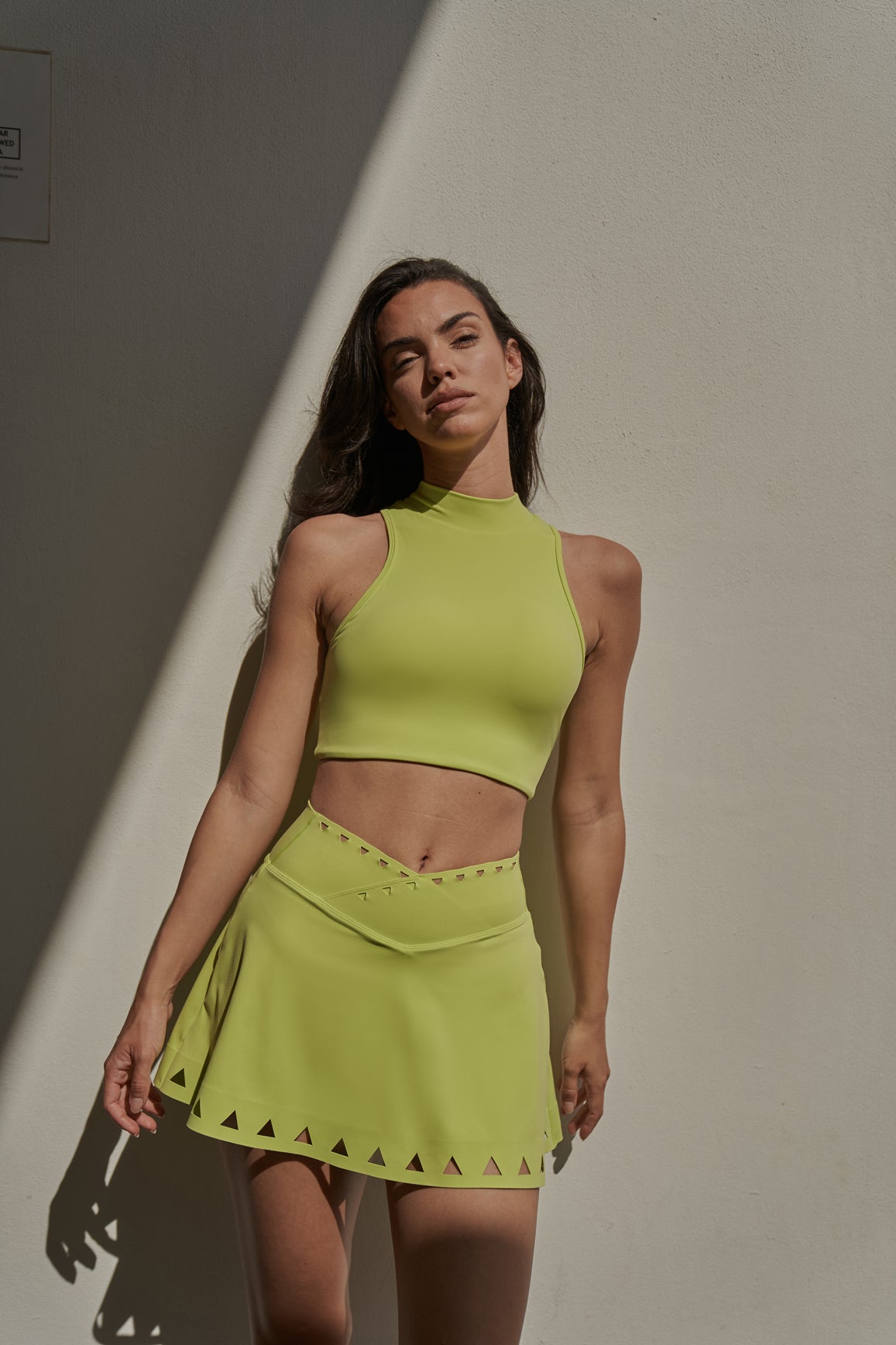 WISKII V-waist laser cut tennis skirt in bright lime green with stylish cut-out details, perfect for athletic or casual wear.