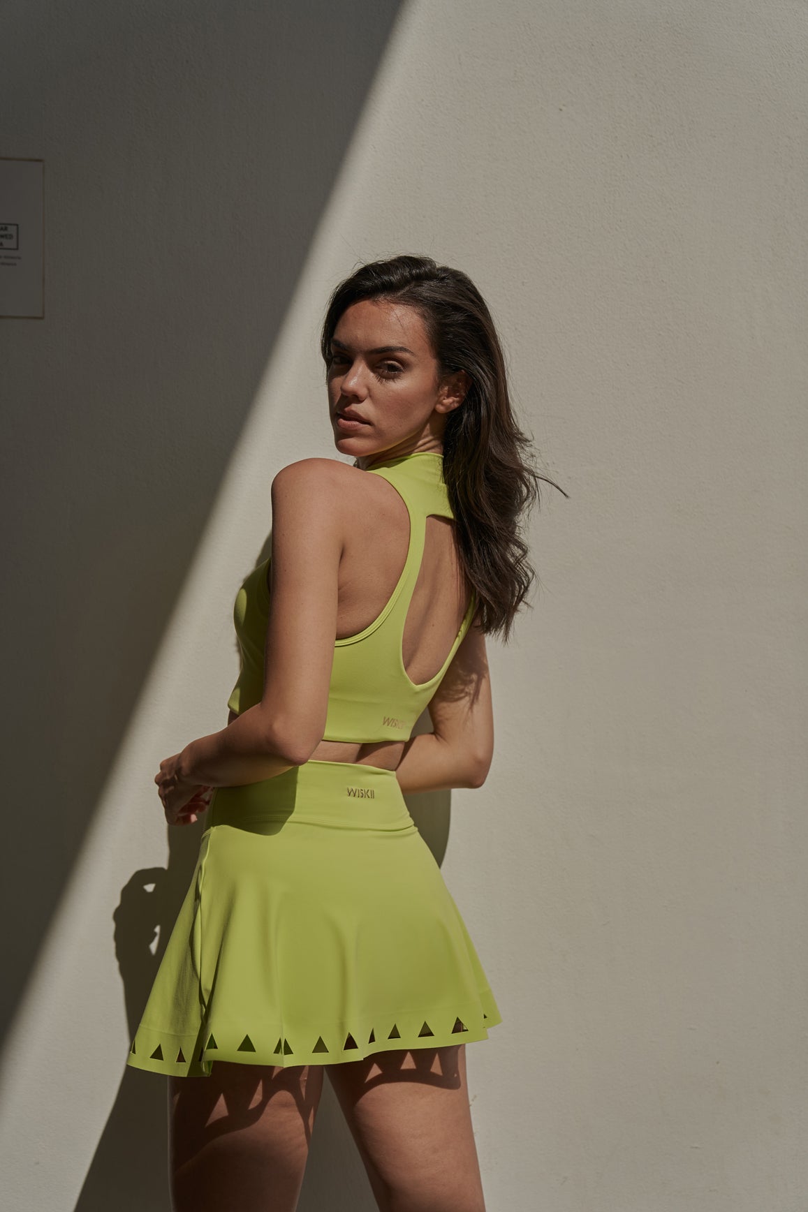 WISKII V-waist laser cut tennis skirt in bitter lime with stylish cut-out details, designed for active tennis wear.