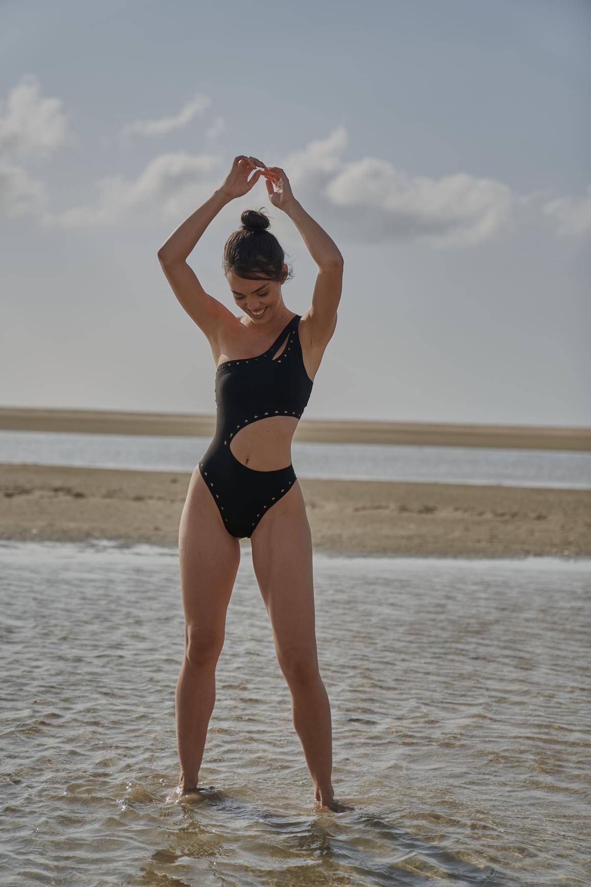 Ivory one-shoulder laser cut swimsuit by WISKII, showcasing the stylish asymmetrical design and intricate cut-out details.