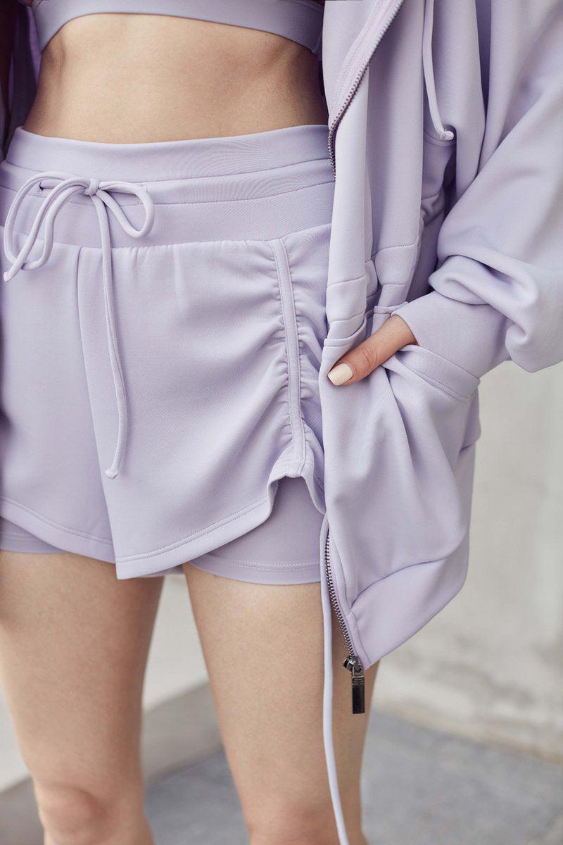 女性用オリーブグリーン WISKII Lustre ショートパンツで、スタイリッシュでフィットしたデザインとカジュアルなシルエットを備え、無地の背景に展示されています