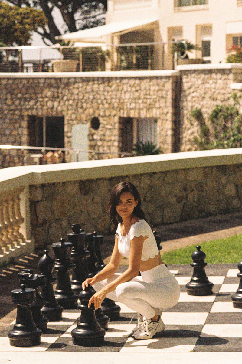 Model wears a Riviera Scallop Off Shoulder Sports Bra | Ivory | WISKII Active