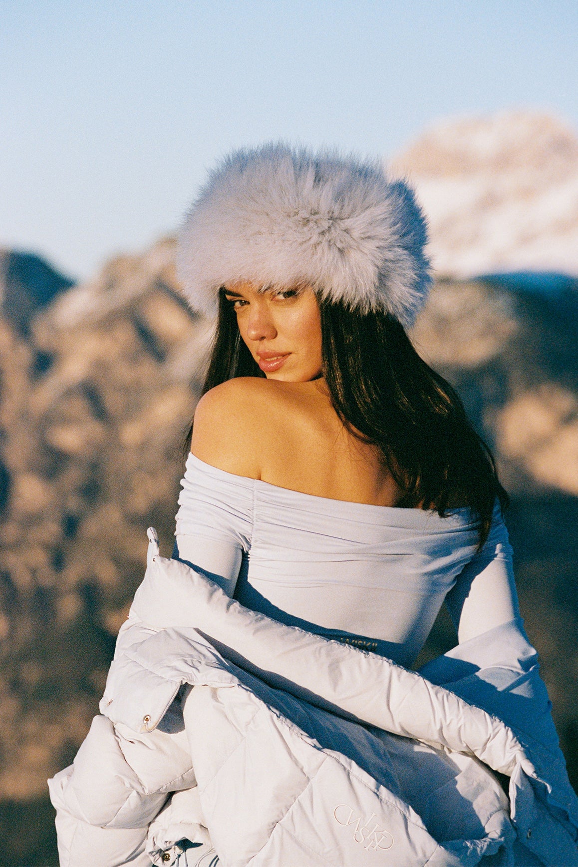 Ivory long sleeve off shoulder pleated bodysuit by WISKII, featuring elegant draping and a fitted silhouette.